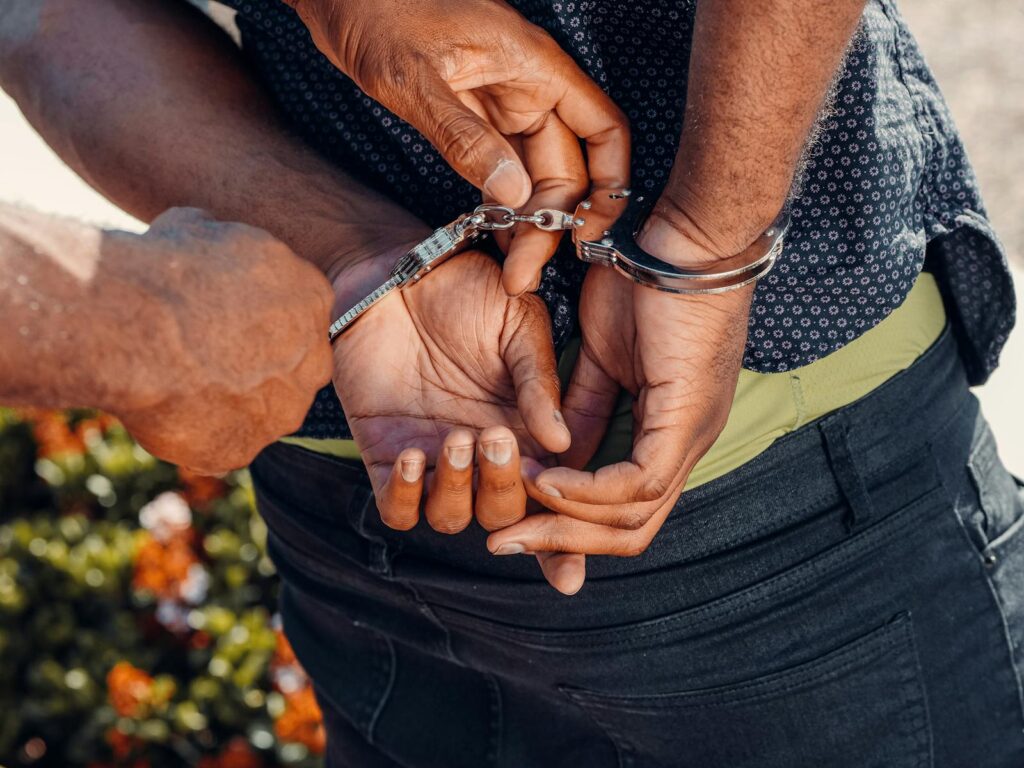 Close-up of a police officer handcuffing a man outdoors. Law enforcement in action.