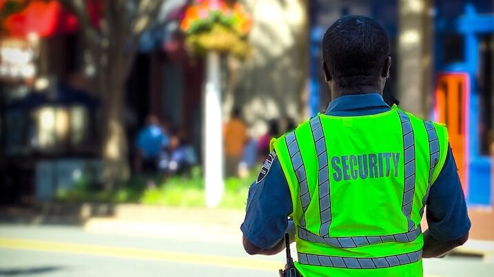 man in green and blue jacket walking on street during daytime