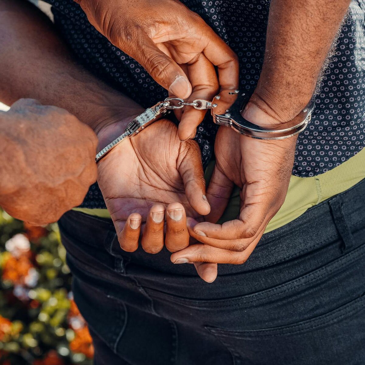 Close-up of a police officer handcuffing a man outdoors. Law enforcement in action.